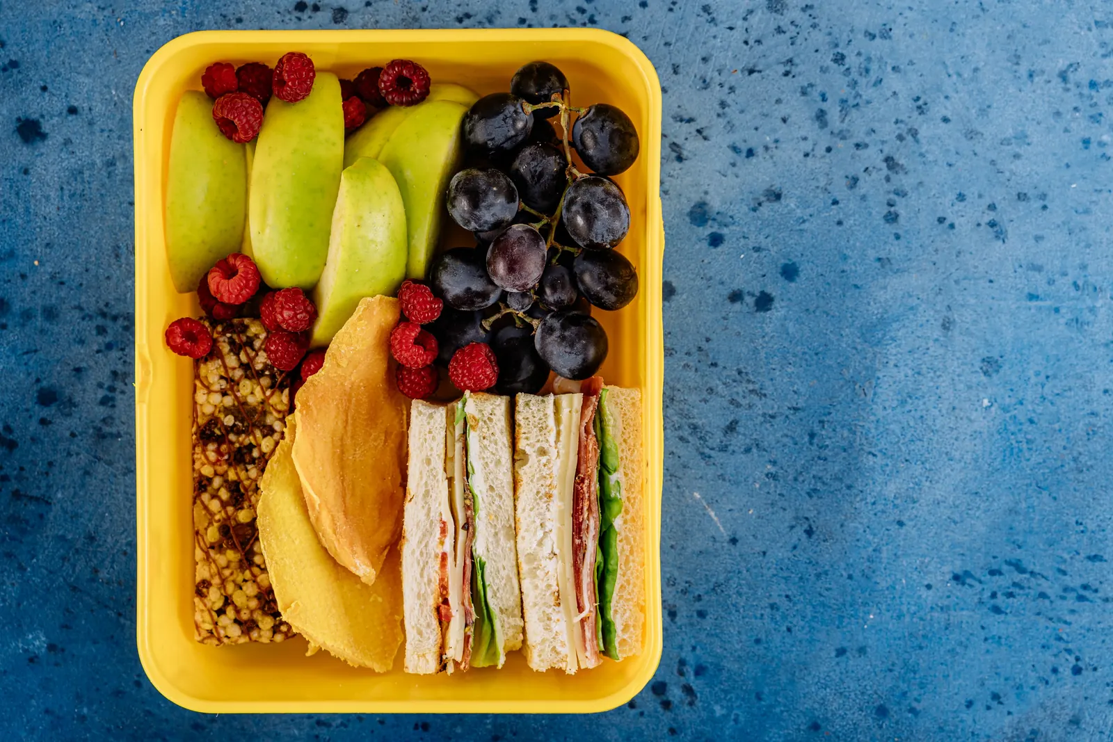 A lunchbox with fruit and sandwiches